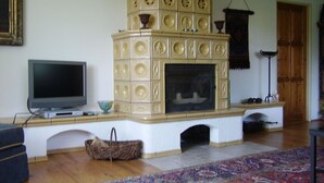 A living room with a fireplace, a television, and a patterned rug. - Spacious villa with fireplace (Vidochov)