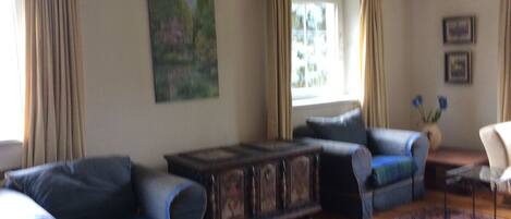 A living room with a sofa set, a coffee table, and a painting on the wall.