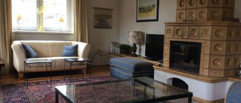 A living room with a sofa, a glass coffee table, a fireplace, and a television.