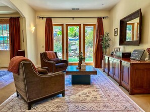 A spacious living room with a large window, a sofa, a coffee table, and a cabinet.