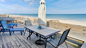 A wooden deck with a table and chairs, overlooking a beach. - Ocean's Edge | Pet-Friendly Oceanfront Home with Direct Beach Access (Ponte Vedra)