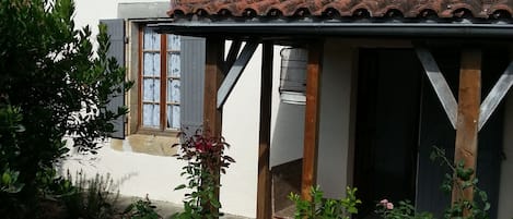A white building with a tiled roof, a covered porch, and a small window.
