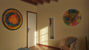 A room with a bed, a chair, and two circular wall art pieces. - Ô Mirror... straightforwardly tell me everything about this trip  (Francescas)