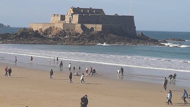 Ein Strand mit einer großen, festungsartigen Struktur auf einem Felsen.