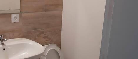 Un baño con lavamanos, inodoro y espejo blancos.