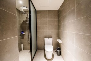 A modern bathroom with a shower, toilet, and a glass partition.