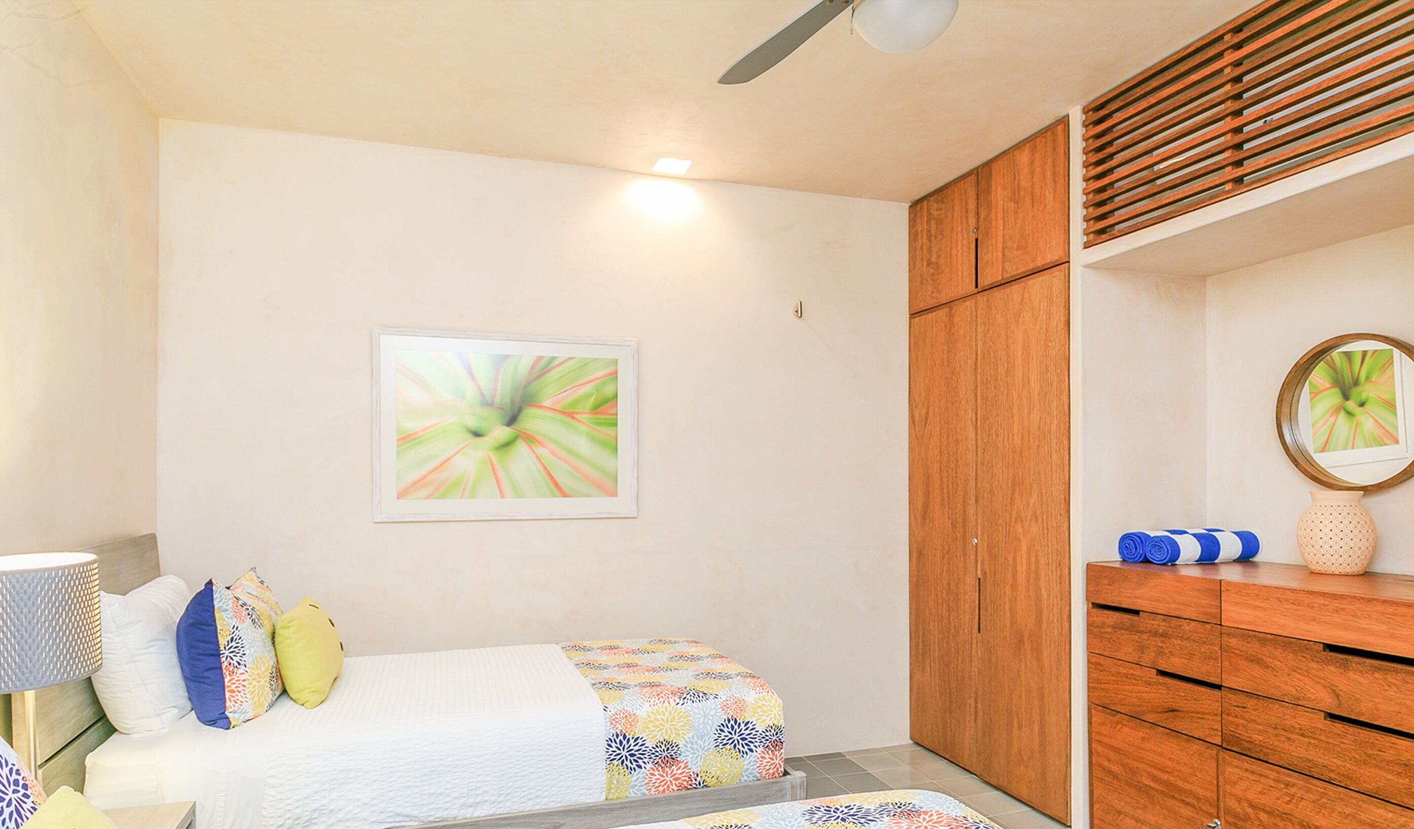 A bedroom with a bed, a wooden wardrobe, a mirror, and a wall-mounted picture.
