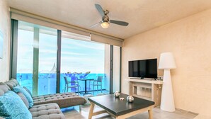 A modern living room with a sofa, a table, a TV, and a balcony with a view of the ocean. - Sabor A Miel by Stella Rentals (Playa del Carmen)