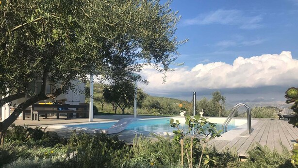 Una piscina con cubierta de madera, rodeada de follaje y vistas al paisaje.
