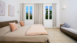 Un dormitorio con cama, sofá y dos ventanas con cortinas.