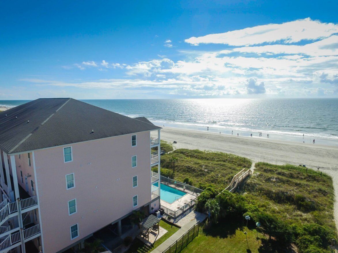 Ein Hotel direkt am Strand mit Pool, Blick auf den Strand und einer Treppe zu den oberen Stockwerken.