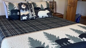 A bedroom with a bed, pillows, a lamp, and a wooden door.