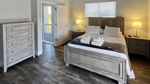 A bedroom with a bed, bedside tables, a dresser, a ceiling fan, and a window. - Spacious condo, great location in paradise! (Key Largo)