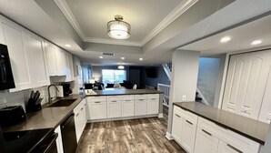 A modern kitchen with white cabinets, a wooden floor, and a central island. - Spacious condo, great location in paradise! (Key Largo)