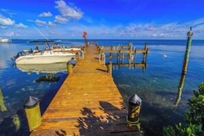 A wooden pier extending into calm waters with a boat docked at the end.
