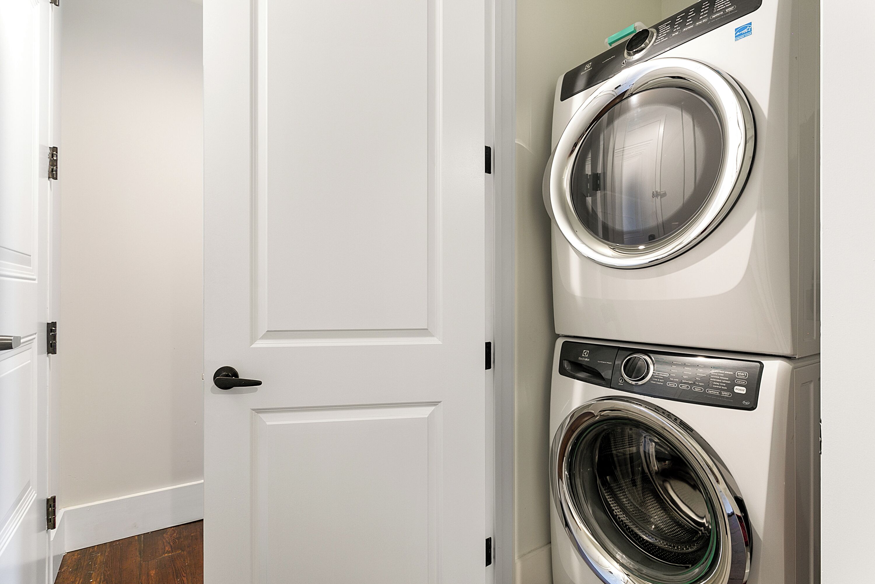 A laundry room with two stacked front-loading washing machines and a white door.