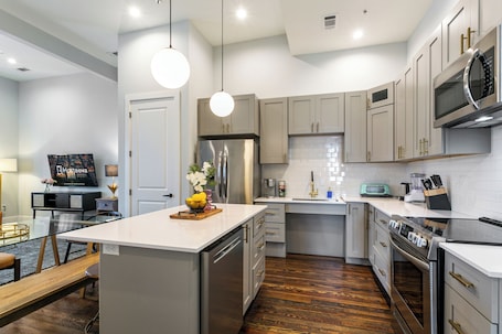 A modern kitchen with stainless steel appliances, a central island, and a wooden floor.