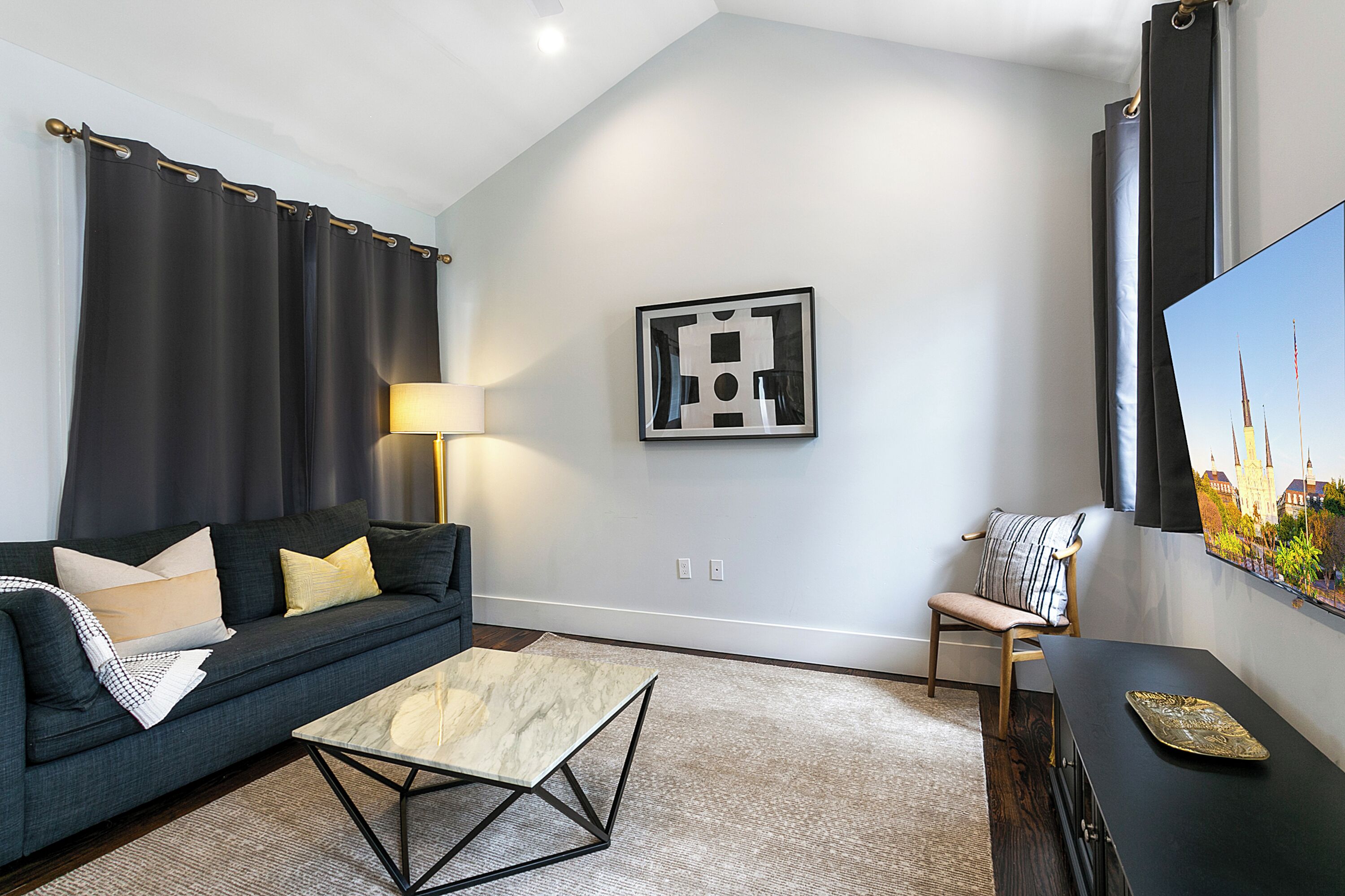 A modern living room with a dark green sofa, a marble coffee table, and a black side table.