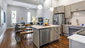 Een moderne keuken met roestvrijstalen apparatuur, een centraal eiland en een eethoek met een glazen tafel en stoelen.