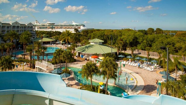 A water park with a large slide, multiple pools, and a cruise ship in the background. - Two Bedroom Lock-off, Luxury Condo, Cape Canaveral, Florida (2563804) (Cape Canaveral)