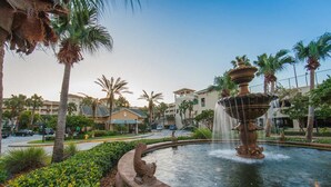 A fountain with a decorative base, surrounded by palm trees and a well-maintained garden. - Two Bedroom Lock-off, Luxury Condo, Cape Canaveral, Florida (2563804) (Cape Canaveral)