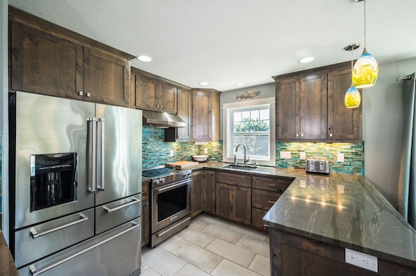 A modern kitchen with stainless steel appliances, wooden cabinets, and a colorful backsplash.