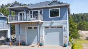 Une maison à deux étages avec un balcon, un garage et une allée.