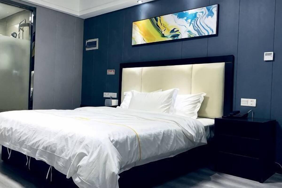Hotellihuone, jossa on suuri sänky, yöpöytä, seinälle ripustettu taideteos ja ovi kylpyhuoneeseen.