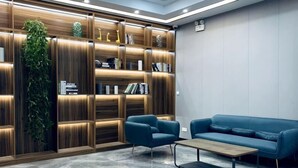 A modern interior with a wooden bookshelf, two blue armchairs, a wooden coffee table, and a marble floor. - Saijia Hotel (Rugao Rt Mart) (Rugao)