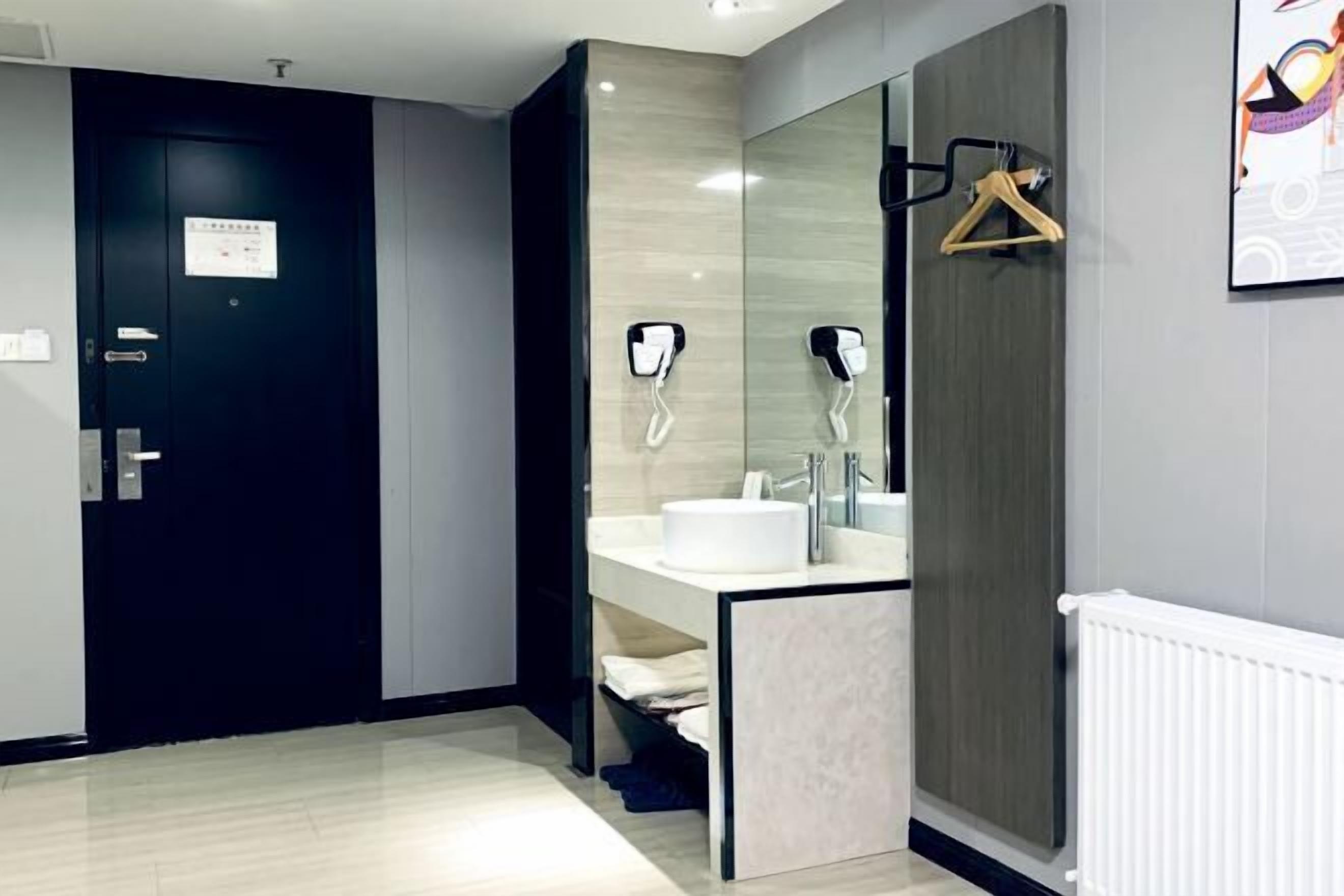 Een moderne badkamer met een donkere deur, een witte wastafel en een handdoekrek.