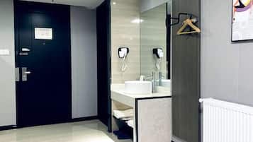 Een moderne badkamer met een donkere deur, een witte wastafel en een handdoekrek.