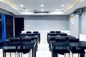 Un salón de conferencias con mesas, sillas, una pizarra y una puerta con un letrero.