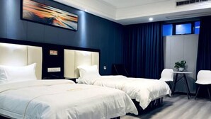 A hotel room with two beds, a desk, chairs, a small table with a plant, and a painting on the wall. - Saijia Hotel (Rugao Rt Mart) (Rugao)