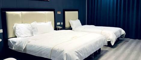 Habitación de hotel con dos camas, una silla blanca, un cuadro en la pared y una cortina azul oscuro.