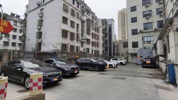 A parking area with multiple cars, a building with balconies, and a red sign.