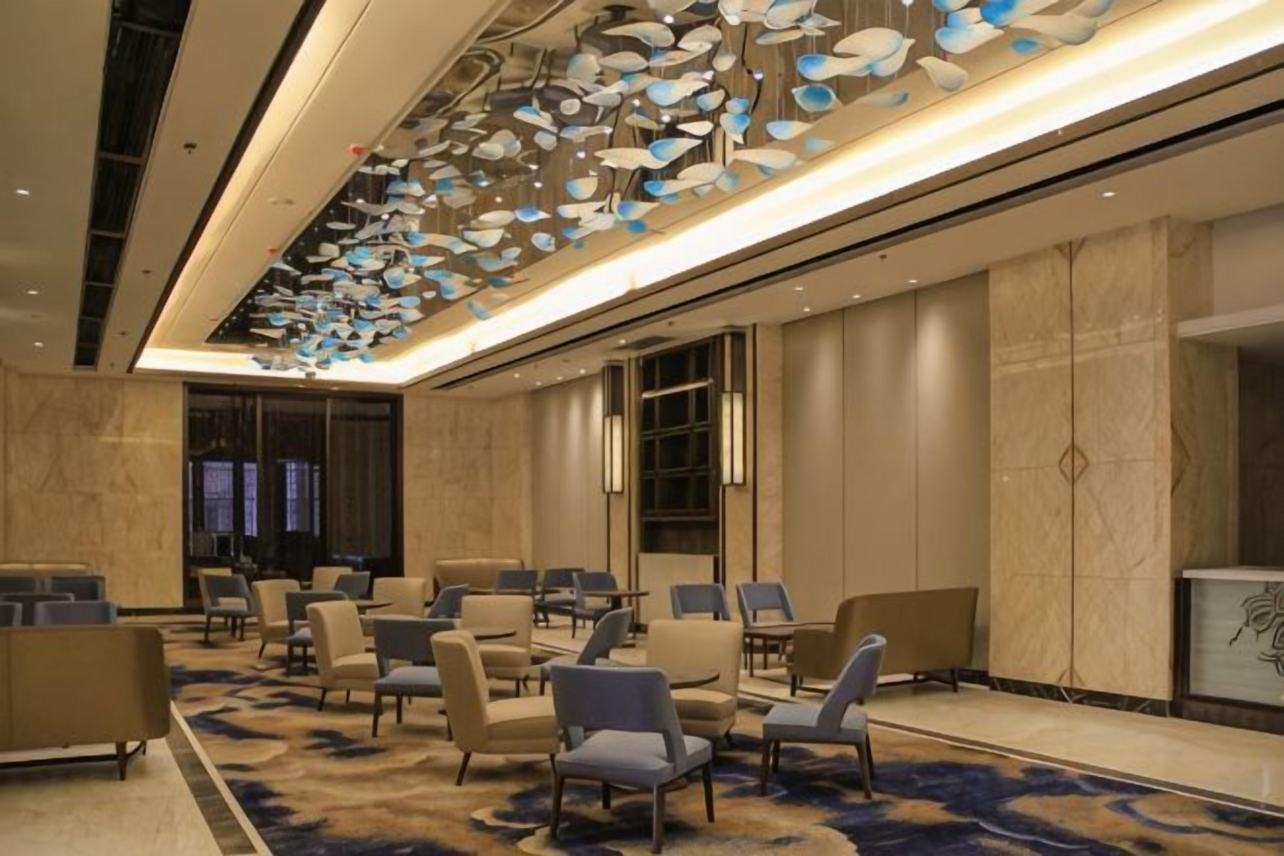 Een hotellobby met een modern design, met een kamerbreed tapijt, een zithoek met stoelen en een decoratief plafond.