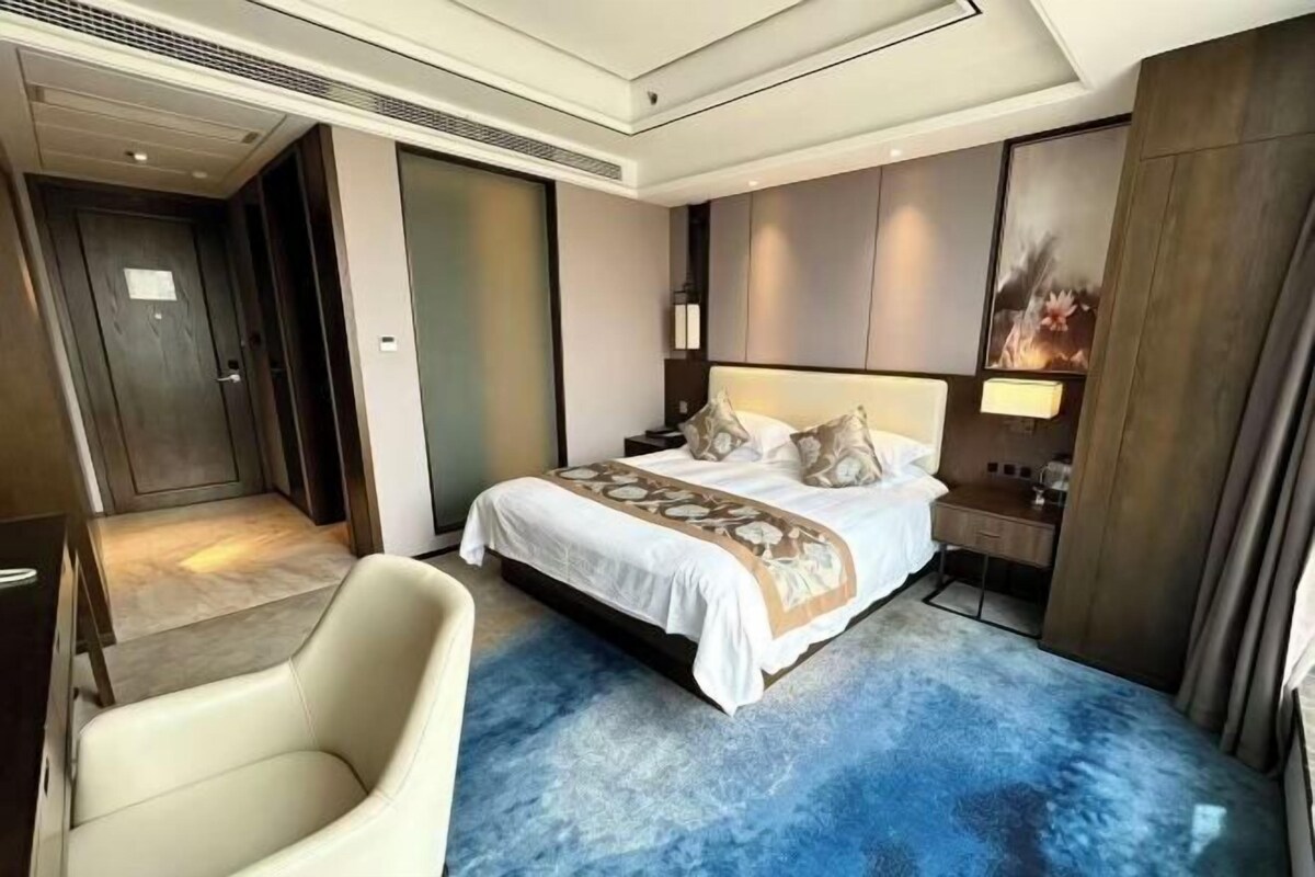 Une chambre d’hôtel avec un grand lit, un bureau et une chaise.