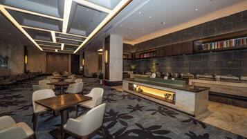 Un moderno vestíbulo de hotel con área de bar, asientos y alfombra estampada.