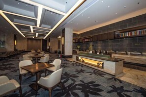 Un moderno vestíbulo de hotel con área de bar, asientos y alfombra estampada.