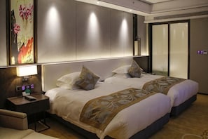 Une chambre d’hôtel avec un grand lit, des tables de chevet, un bureau et un téléviseur fixé au mur.