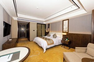 Una habitación de hotel con cama, escritorio, silla y televisión.