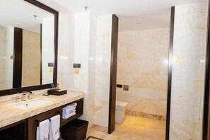 Un baño moderno con lavamanos de mármol, un espejo grande y un área de ducha independiente.