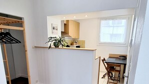 A modern apartment with a wooden floor, a kitchen area, and a dining space.