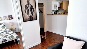 A modern living room with a grey sofa, a framed zebra artwork, wooden flooring, and a view into the kitchen area.