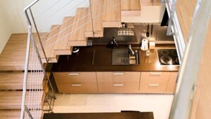 A modern kitchen with wooden cabinets, a black countertop, and stainless steel appliances. - San Sebastián de los Reyes – Loft with 2 Bedrooms (San Sebastián de los Reyes)