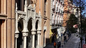 A narrow street with historic buildings, a pedestrian walkway, and parked scooters. - Charming Gran Vía V - in the City Center (Madrid)