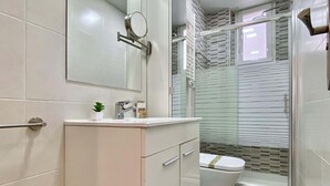 A modern bathroom with a toilet, sink, and shower area. - Charming Atocha - Temporary stays (Madrid)