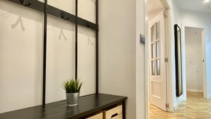 A hallway with a dark wooden bench, a potted plant, and a door leading to another room. - Charming Atocha - Temporary stays (Madrid)