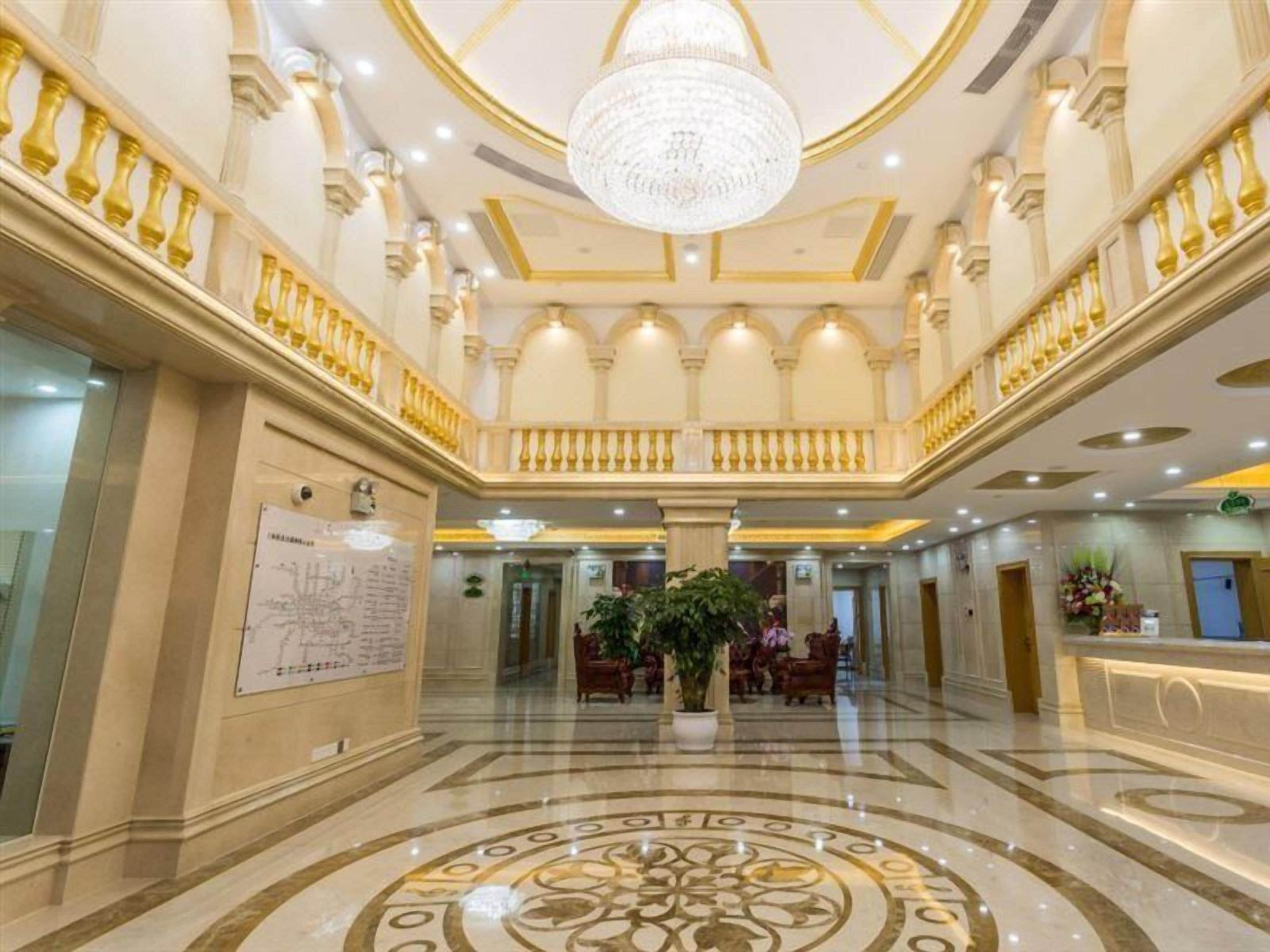 Um hall imponente com lustre, piso de mármore e balcão de recepção.