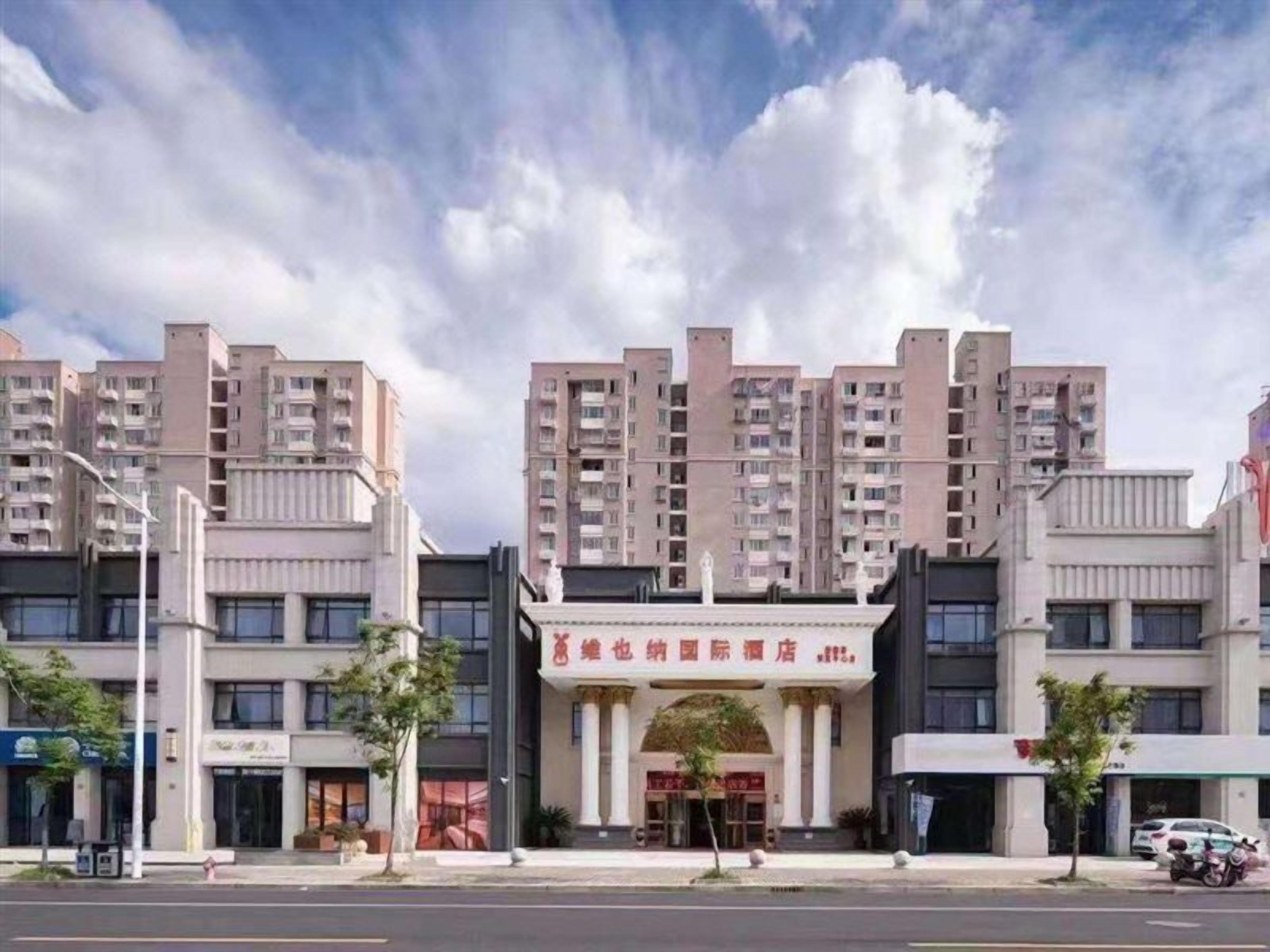 Ein mehrgeschossiges Hotel mit einem zentralen Eingang, umgeben von anderen Gebäuden.